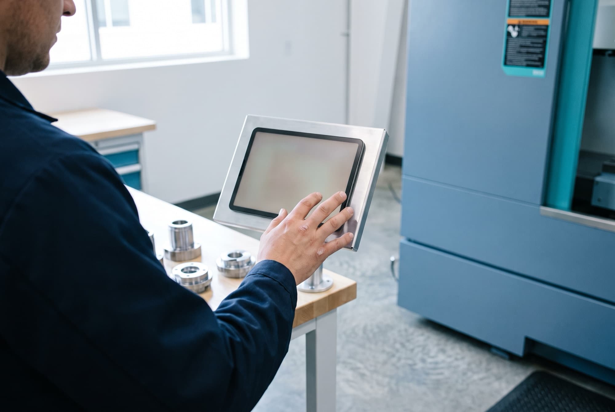 Opérateur touchant une tablette fixée à côté d'une machine pour déclarer sa production à l'atelier